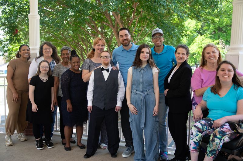 A large group of friends and family poses together in a park gazebo.